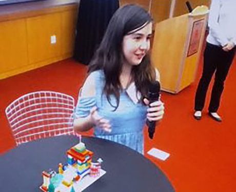 A photo of an elementary student presenting her Lego playground project. 