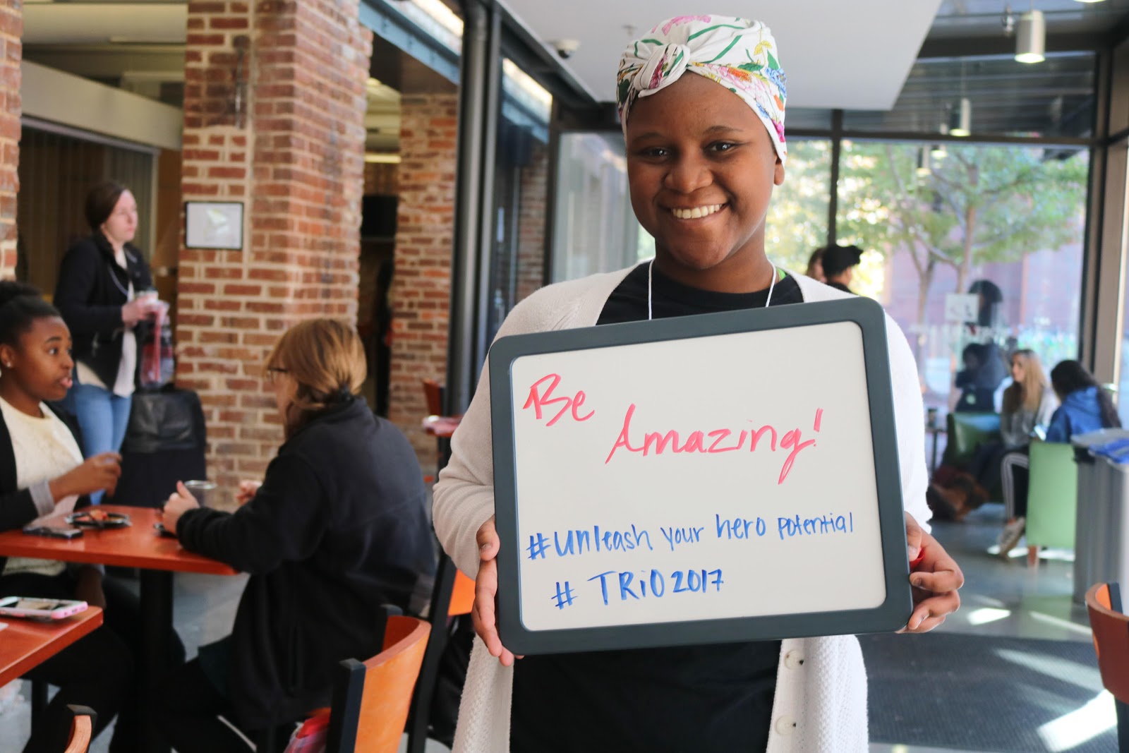 A photo of an NC State student holding up a whiteboard that reads "Be Amazing"