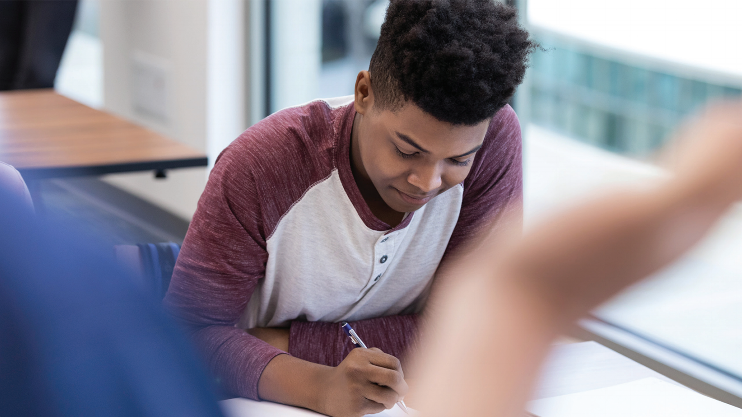 A photo of a teenage student writing at a desk