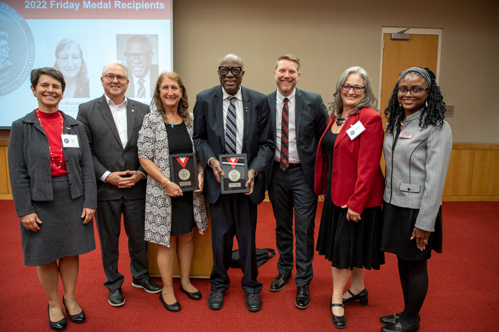 Friday Medal winners Joann Blumenfeld (center left) and Dr. James A. Banks (center right) hold their Friday Medal awards with ceremony speakers (from L to R) Dean Paola Sztajn, Chancellor Randy Woodson, Shaun Kellogg, Hollylynne Lee and Callie Edwards.