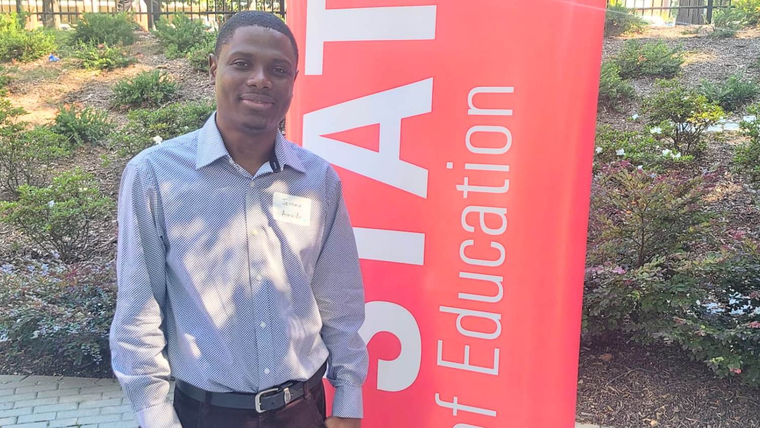 Jerome Amedu standing by an NC State College of Education sign.