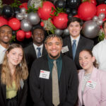 A group of seven scholarship recipients standing in front of a balloon backdrop at the NC State College of Education's Scholarships Banquet