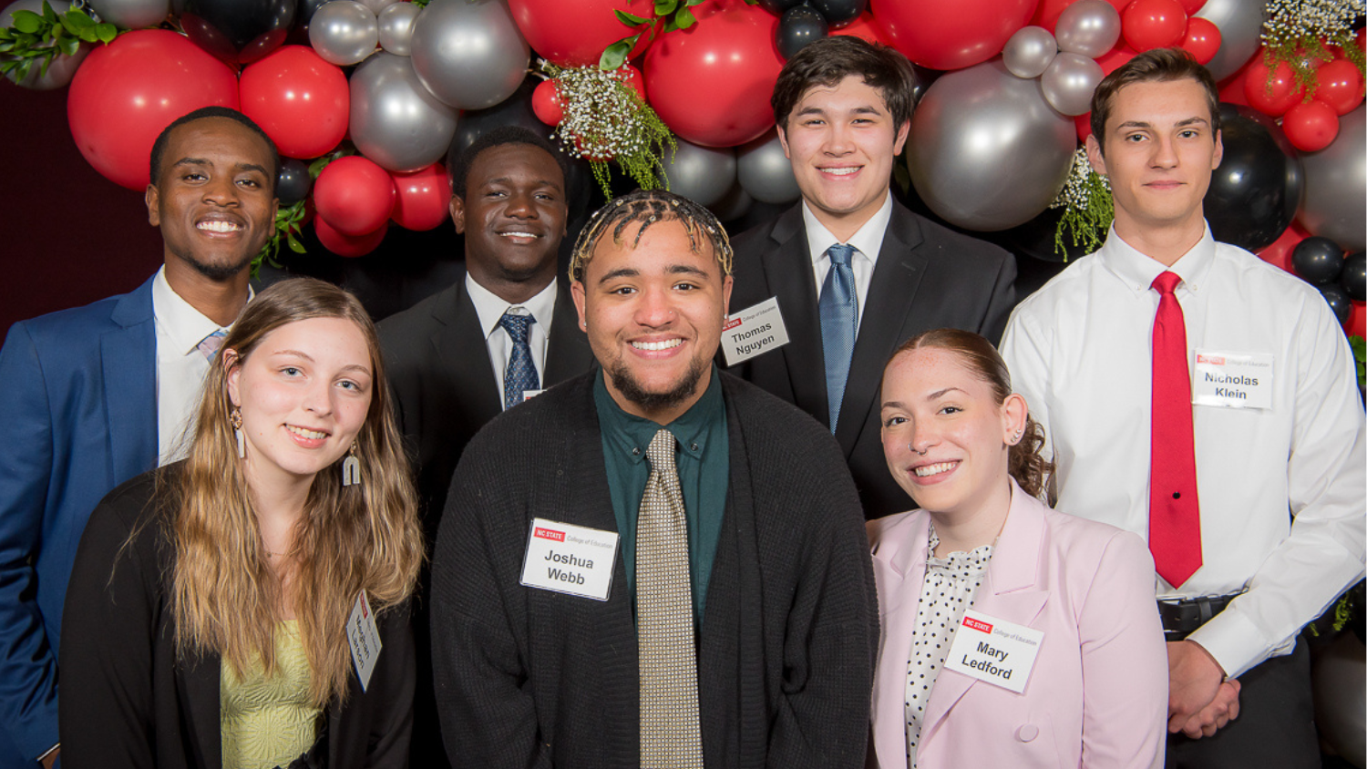 A group of seven scholarship recipients standing in front of a balloon backdrop at the NC State College of Education's Scholarships Banquet