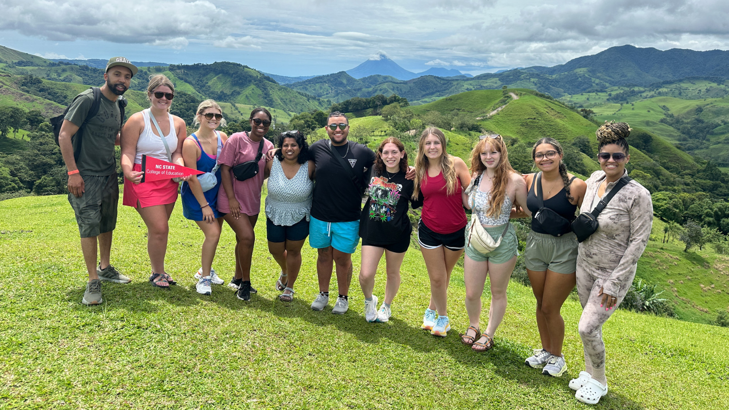 A group photo of the Transformational Scholars standing in front of a scenic vista overlooking mountains that are thick with vegetation.