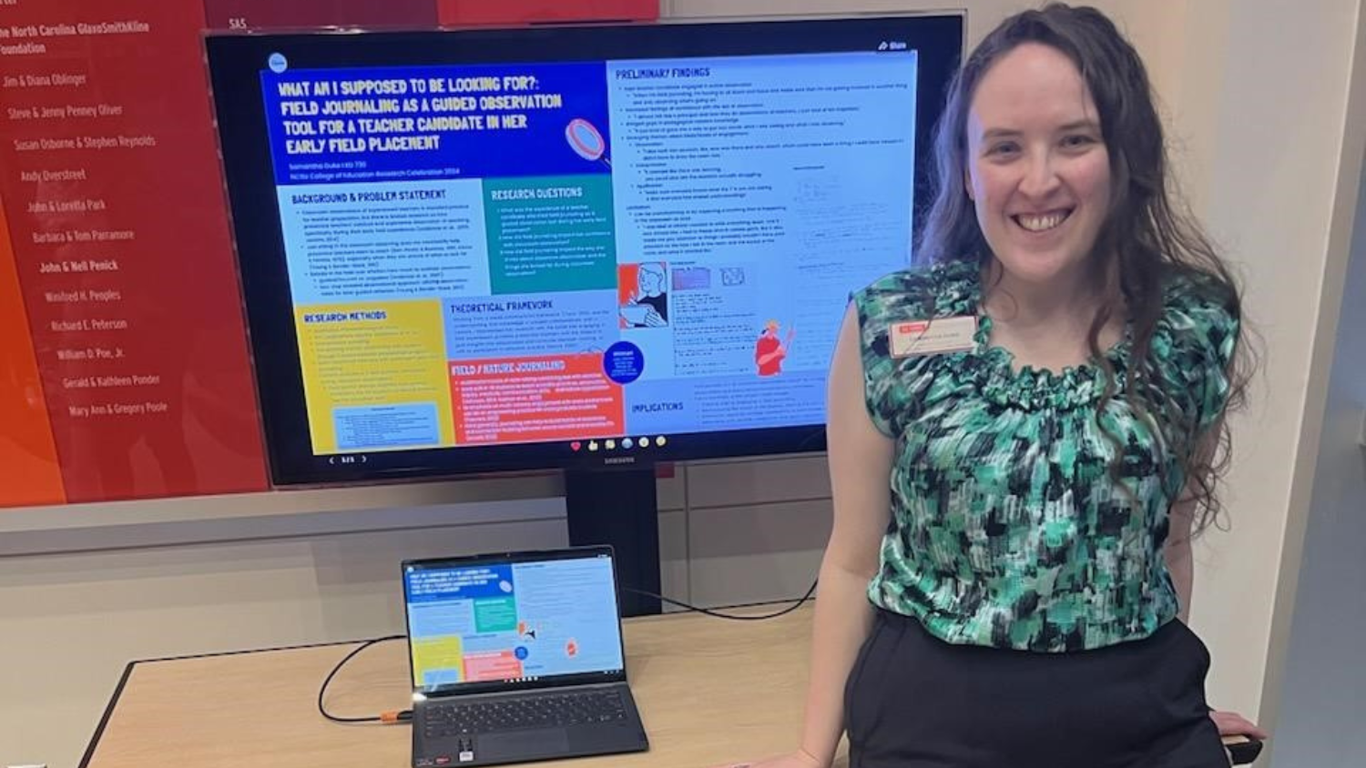 Samantha Duke sitting in front of a screen displaying research.