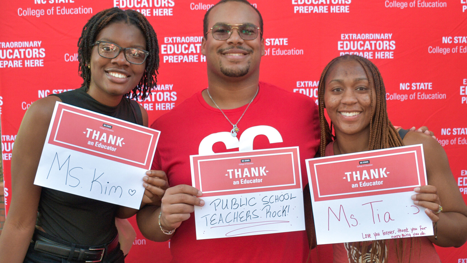 students holding up thank an educator signs