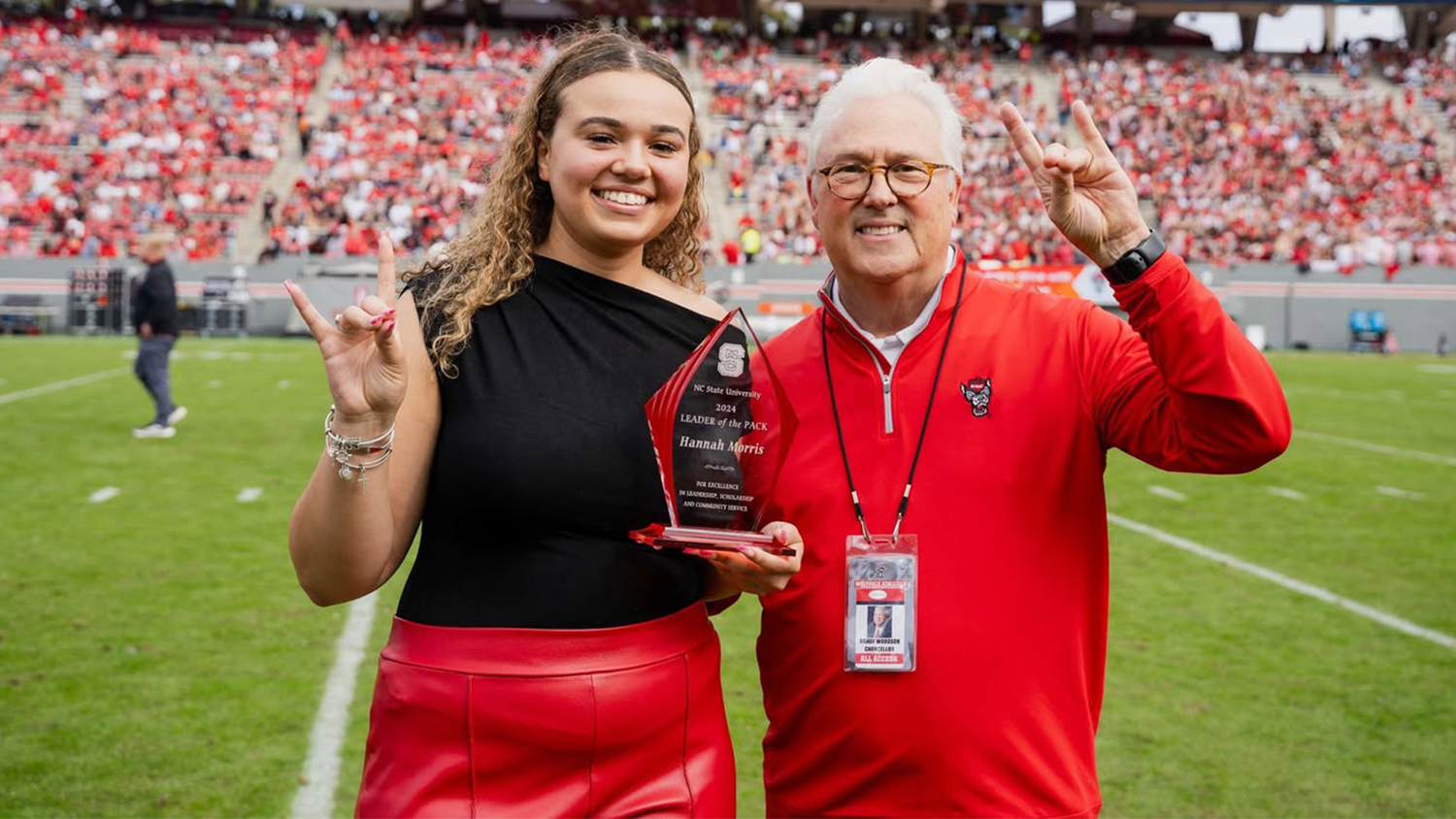 Goodnight Scholar and Applied Education Studies Major Hannah Morris Standing next to Chancellor Randy Woodson as She is Honored on field at Carter-Finley Stadium as Leader of the Pack.