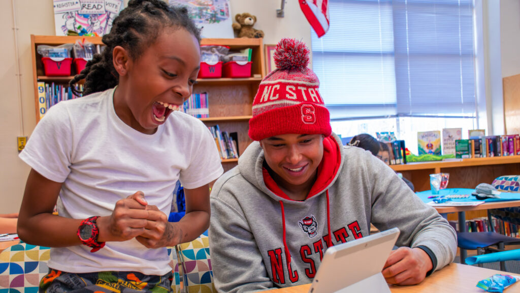 Braxton Cumbo, a Transformational Scholar and N.C. Teaching Fellow who is majoring in technology, engineering and design education, uses a tablet to help his student with a lesson.