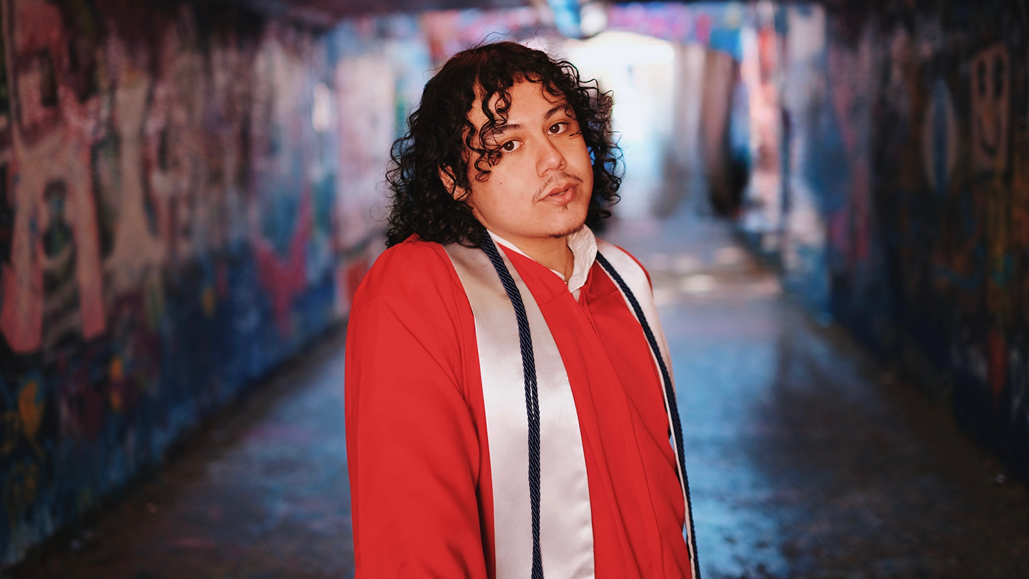 Diego Alonso-Garcia wearing his graduation regalia in the NC State Free Expression Tunnel.