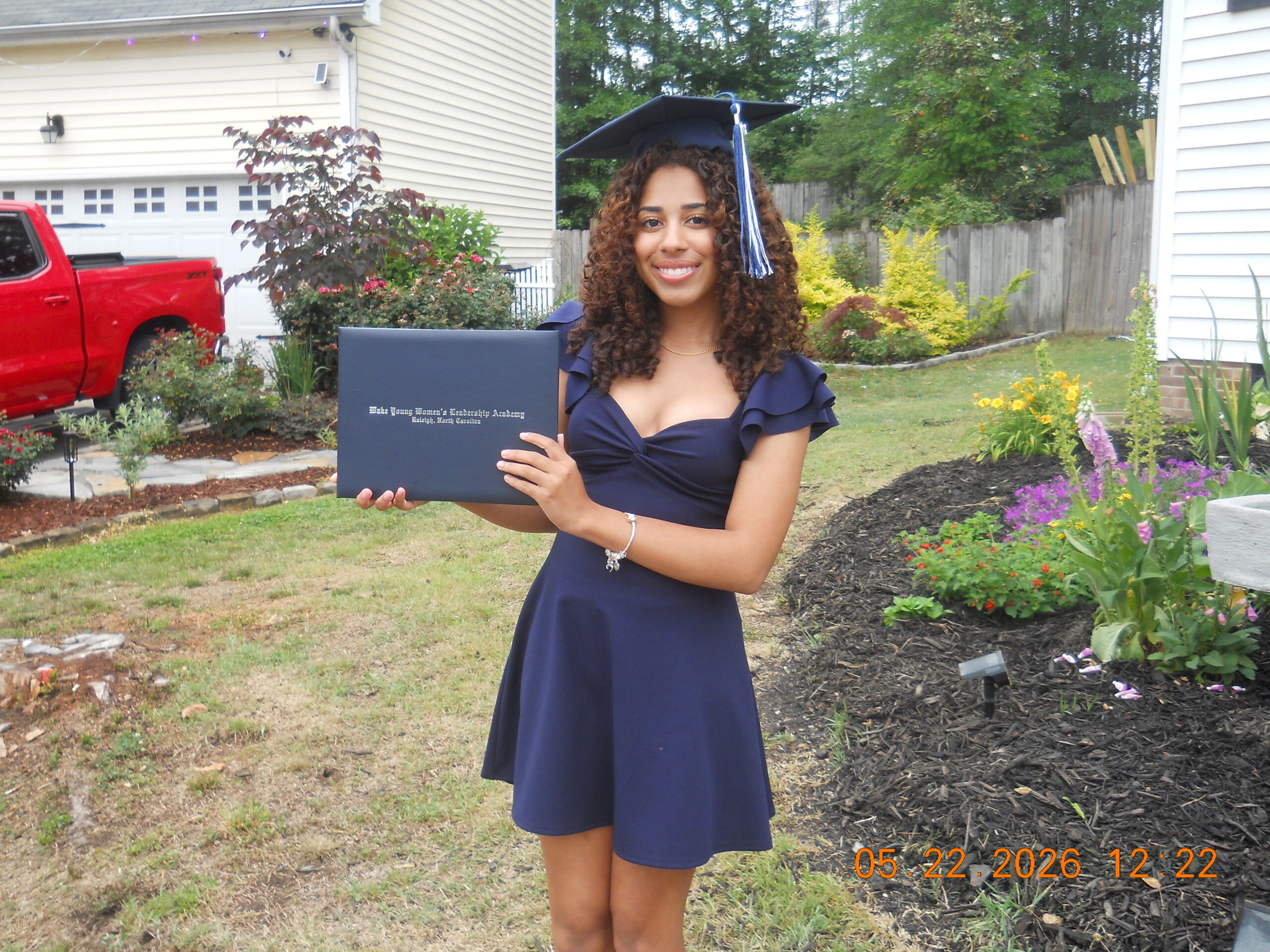 Carolina Mitchell wears a graduation cap and holds her high school diploma. 