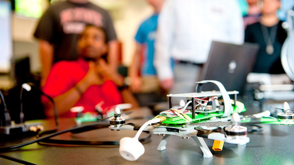 A small robot on a desk in a classroom.