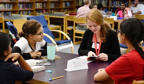 Three middle school students listen in as an NC State Education student guides a book discussion