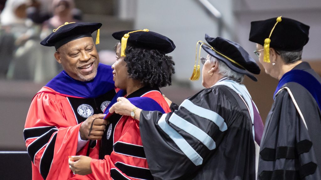 A photo of an NC State Education graduate being hooded at graduation