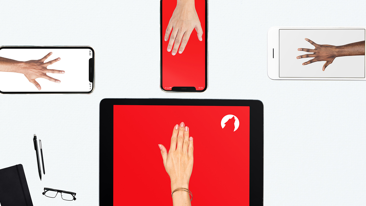 Four hands sitting on top of four separate electronic devices