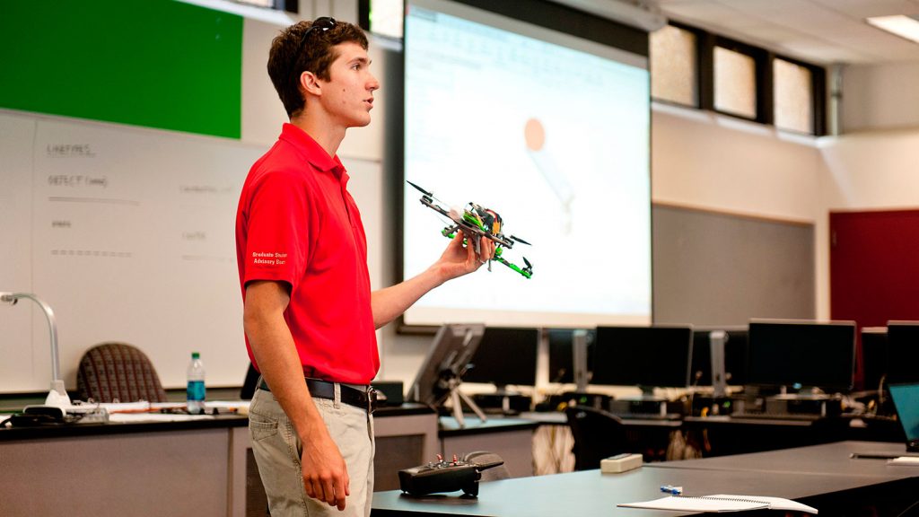 Tech class teacher holding drone to classmates
