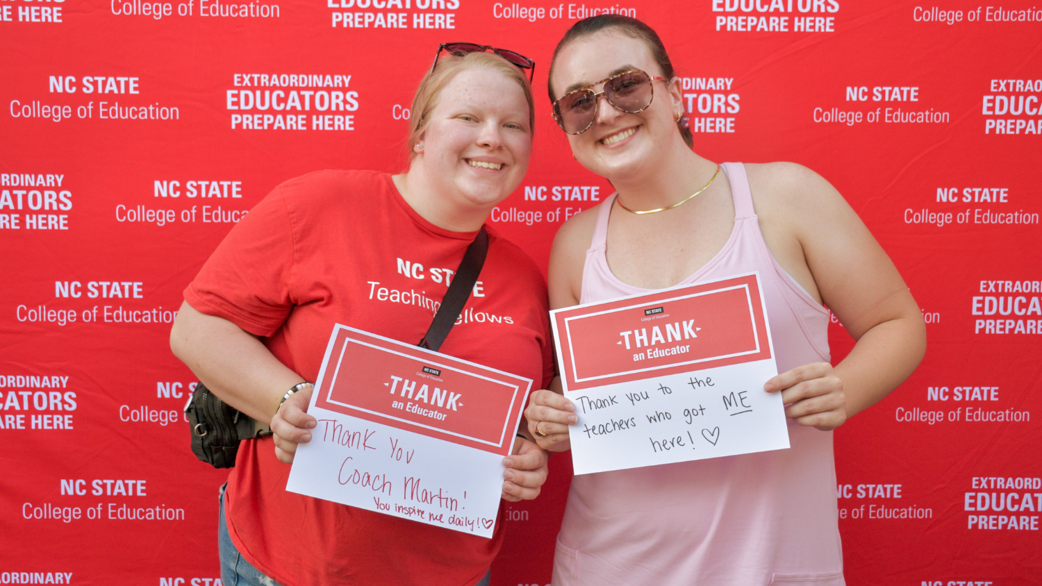 Two students with Thank an Educator signs